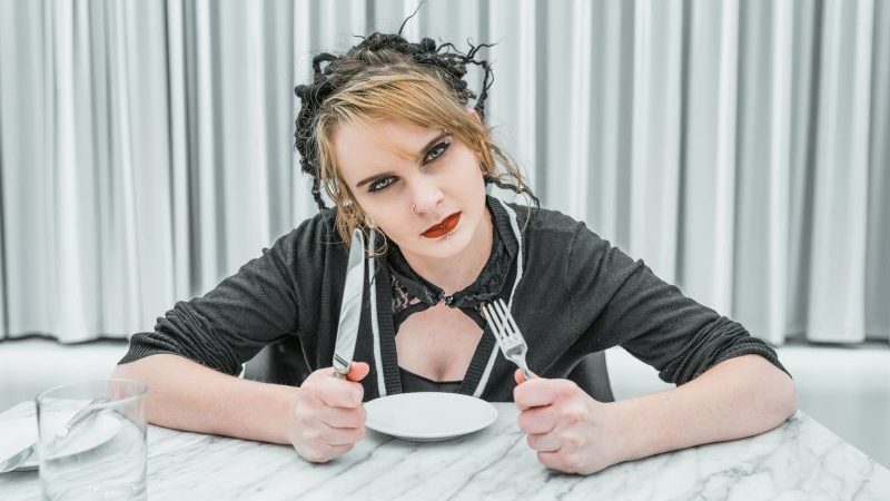 acalmar o cliente nervoso: mulher sentada à mesa segurando garfo e faca