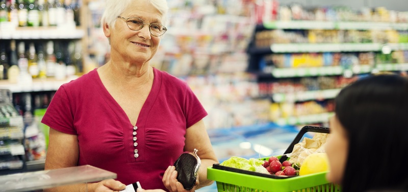 Senhora de idade passando compras em caixa de supermercado