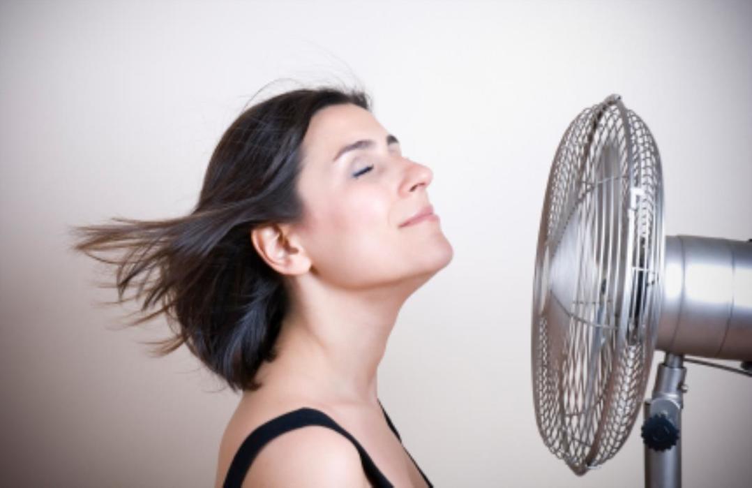 Mulher em frente a um ventilador com os cabelos voando