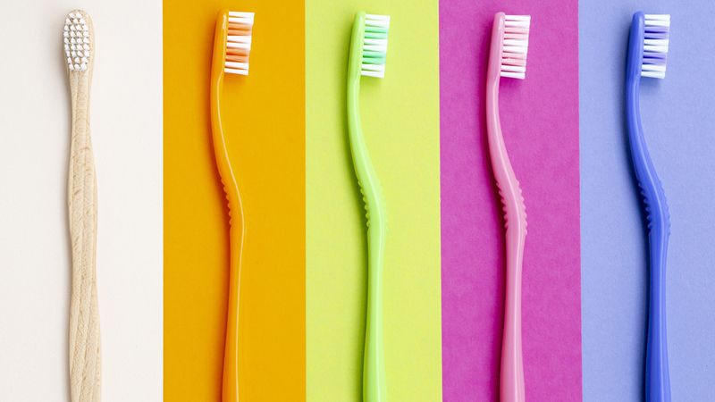 Escovas de dentes coloridas enfileiradas, com uma diferente, em cor natural