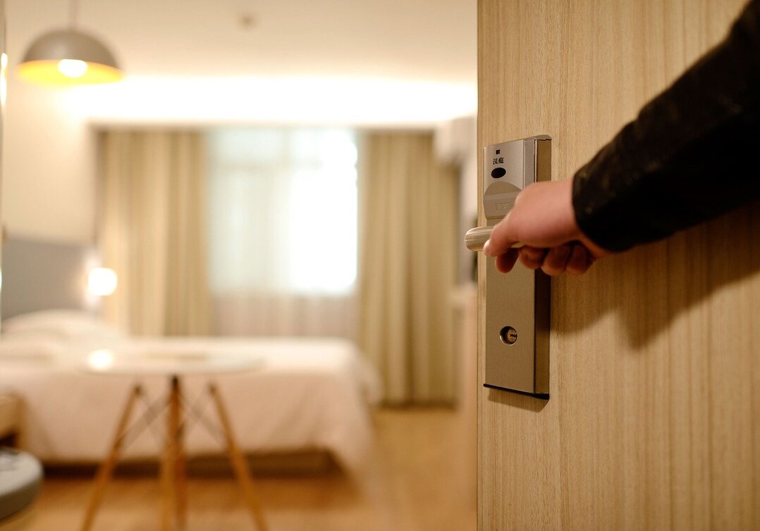 Funcionário de hotel abre a porta do quarto para hóspedes