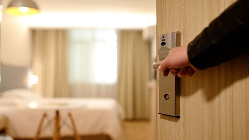 Funcionário de hotel abre a porta do quarto para hóspedes