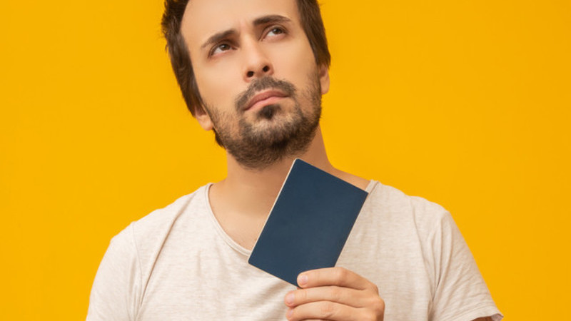  Em um fundo amarelo, um homem está preocupado segurando a sua carteira de trabalho. 