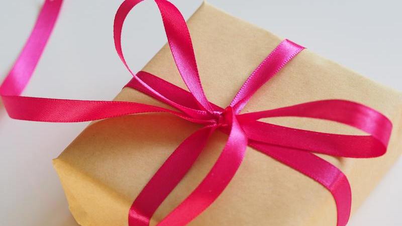 Pacote de presente com laço de fita cor de rosa e embrulho de papel craft. 