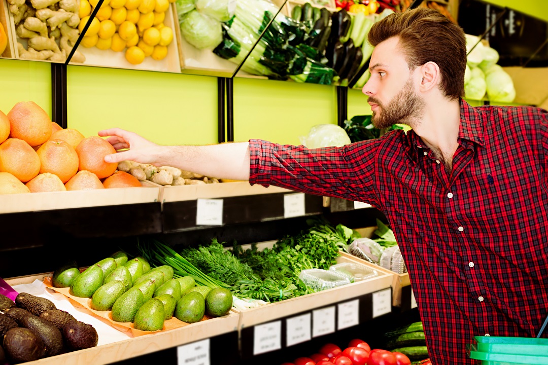 Homem com camisa xadrez vermelha escolhendo FLV no supermercado
