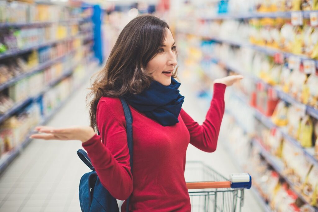 Mulher em supermercado fazendo gesto de surpresa