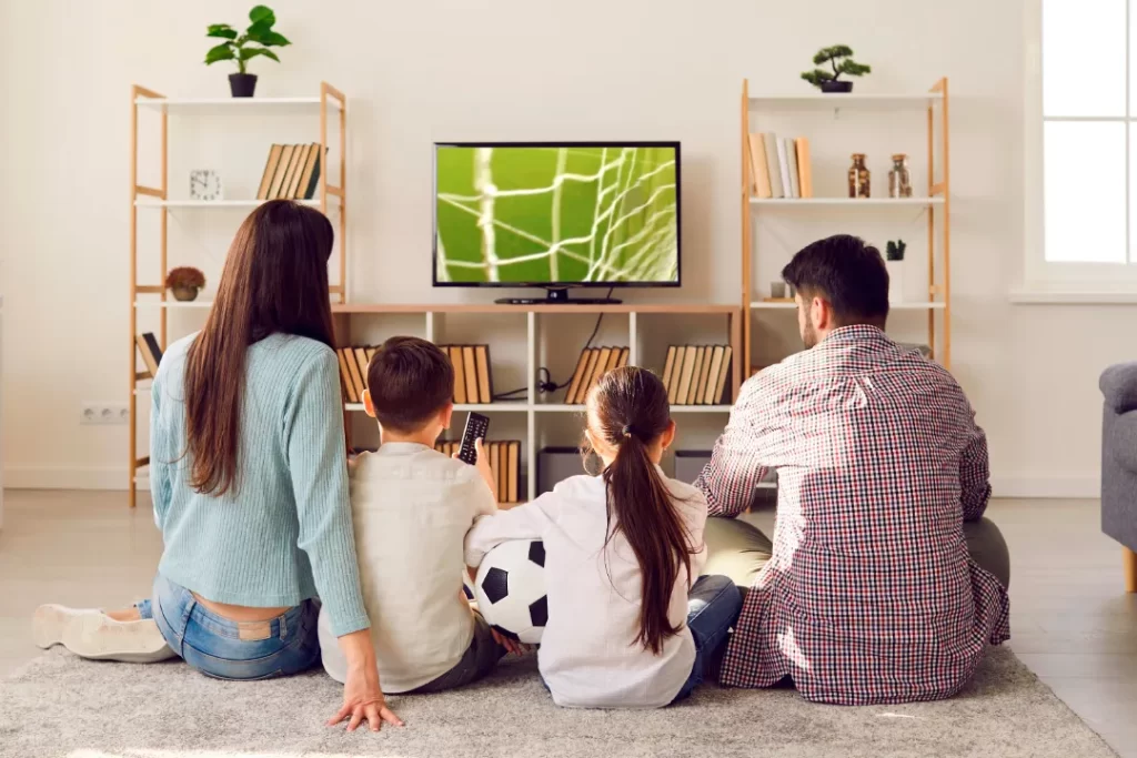 família vendo futebol pela televisão
